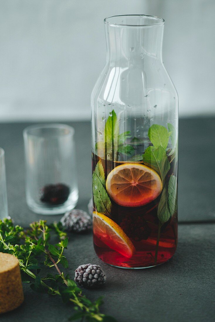 Aromatisiertes Wasser mit Beeren, Kräutern und Zitronen in Glasflasche