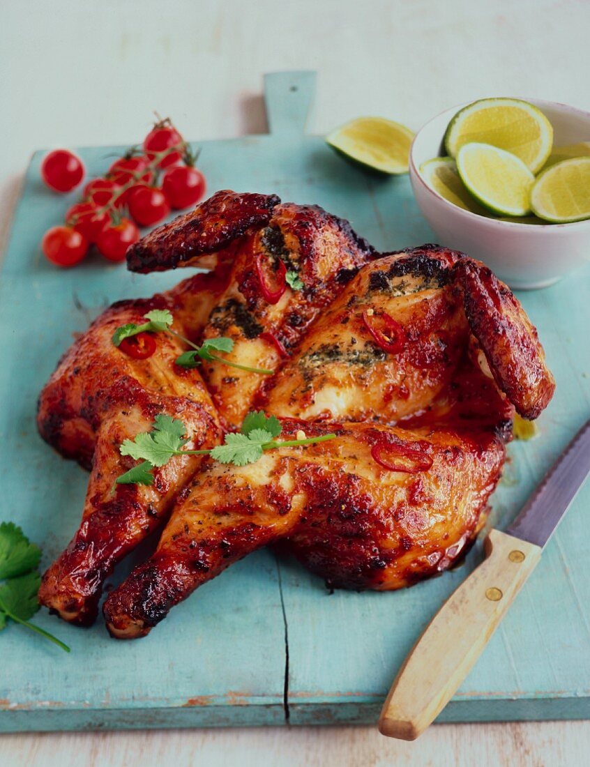 Spicy butterfly chicken with chilli on a wooden chopping board