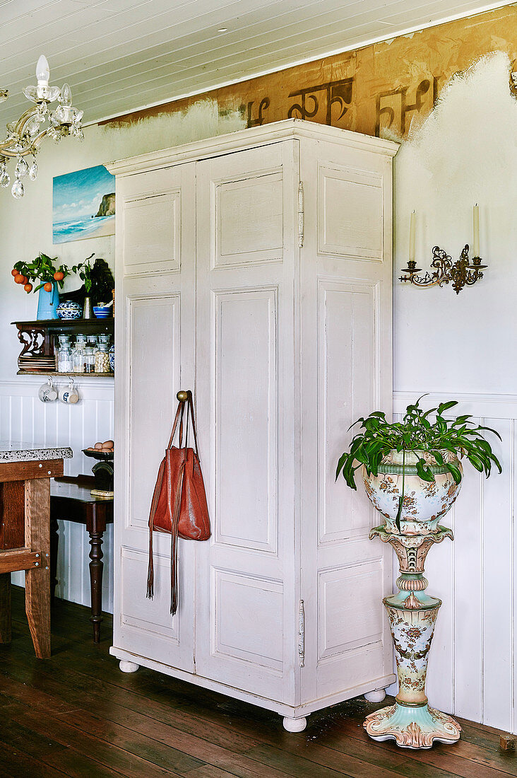 White wardrobe next to antique porcelain planter