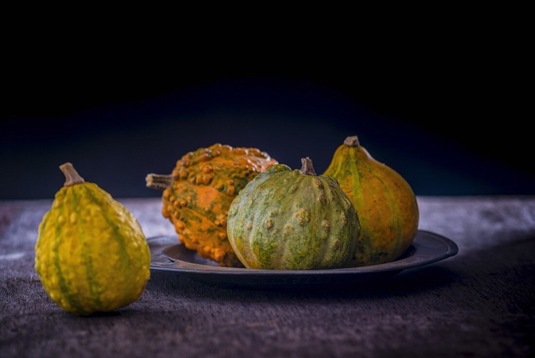 Various pumpkins on and beside a metal plate