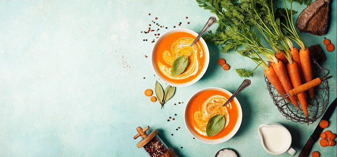 Carrot soup in white bowls on blue background