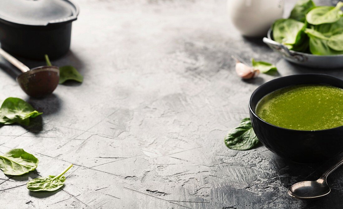 Spinach soup and ingredients on rustic background