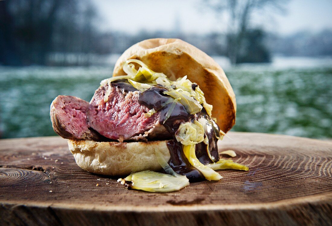 A burger with sauerkraut on a tree stump outdoors (camping)