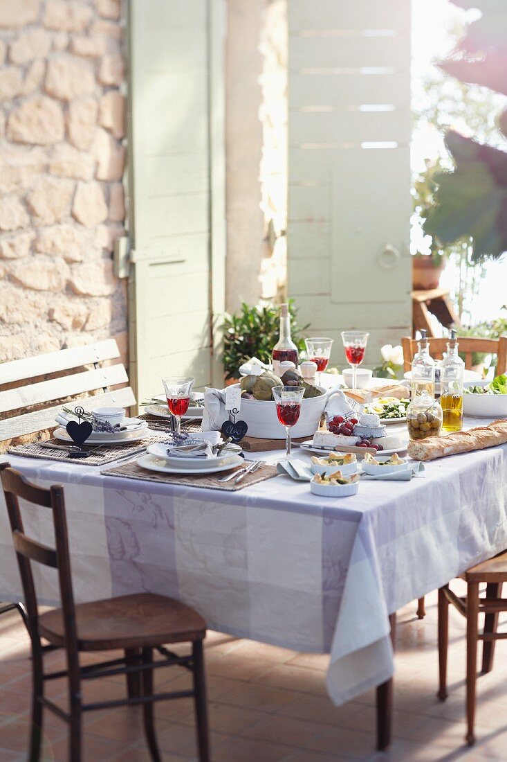 Gedeckter Tisch mit Wein auf sommerlicher Terrasse (Provence, Frankreich)
