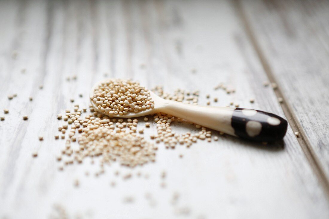 Quinoa auf Löffel und weißem Holzuntergrund