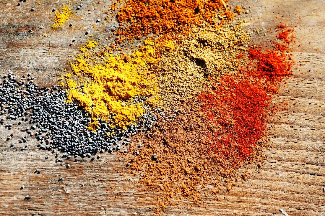 Various spices and poppyseeds on a wooden surface