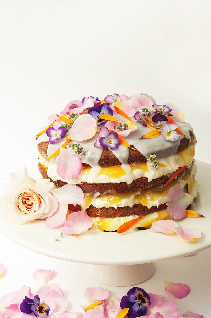 Layered lemon drizzle cake decorated with icing and edible flowers