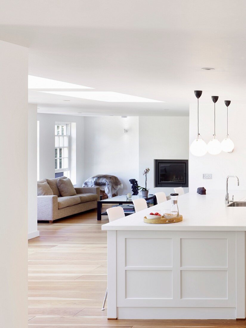 weiße Kücheninsel und Blick in reduzierten Wohnbereich