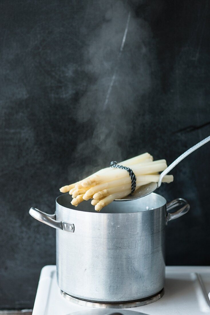 Cooked asparagus being lifted out of the saucepan