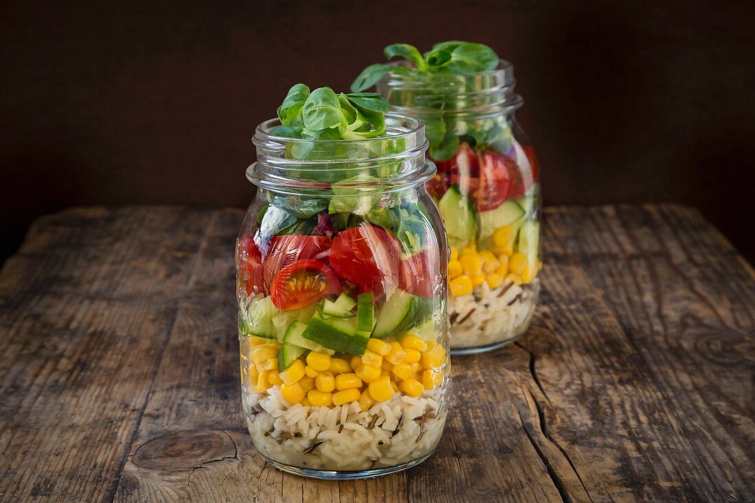 Rice salad in a glass jar with wild rice, sweetcorn, cucumber, tomato and lamb's lettuce