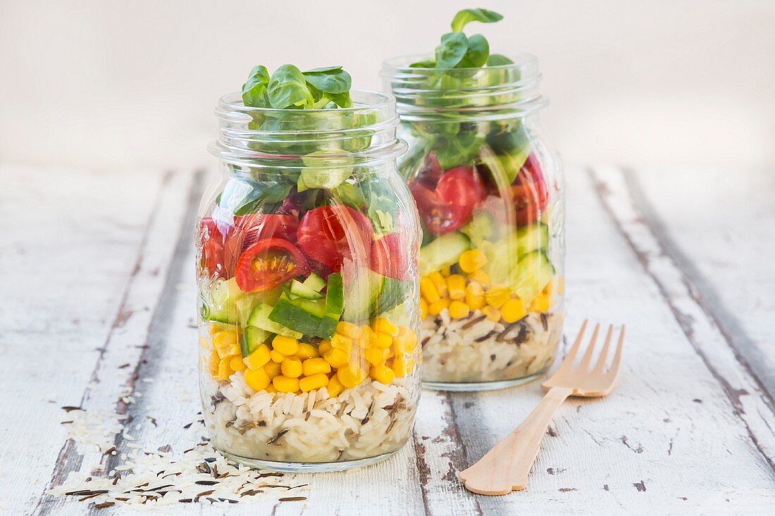 Reissalat im Glas mit Wildreis, Mais, Salatgurke, Tomaten und Feldsalat