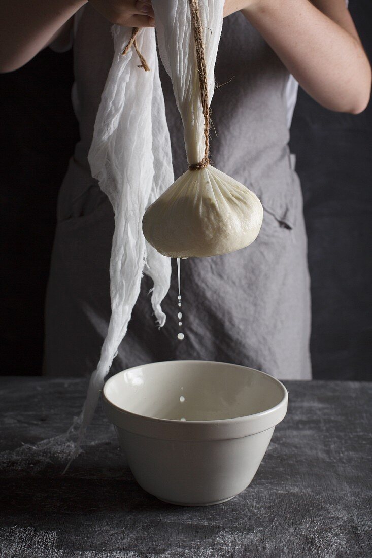 Ricotta in a cheesecloth draining into a bowl