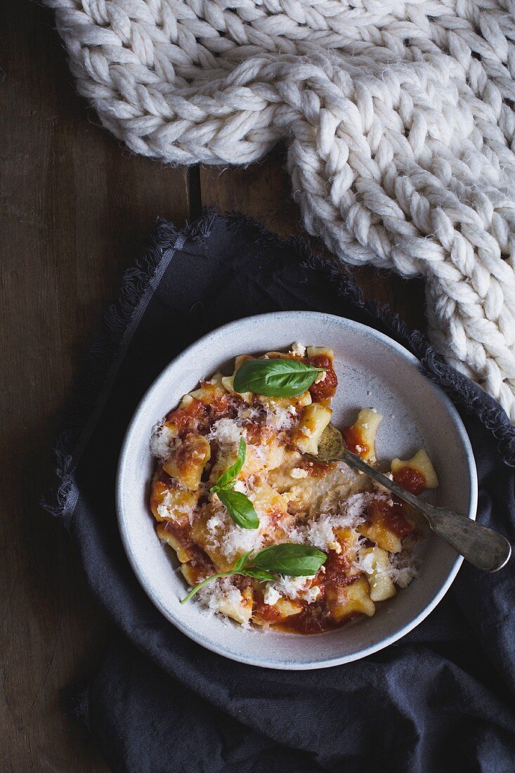 Ricottagnocchi mit Tomatensauce, gebratenem Knoblauch, Zwiebeln, Parmesan und Basilikum