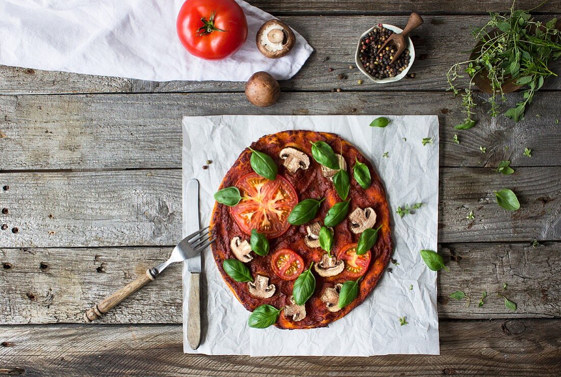 Glutenfreie Pizza mit Tomaten, Champignons und Basilikum (Aufsicht)