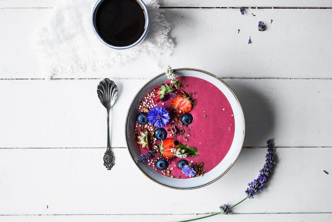 Smoothie-Bowl mit Früchten, Essblüten und glutenfreiem Müsli (Aufsicht)