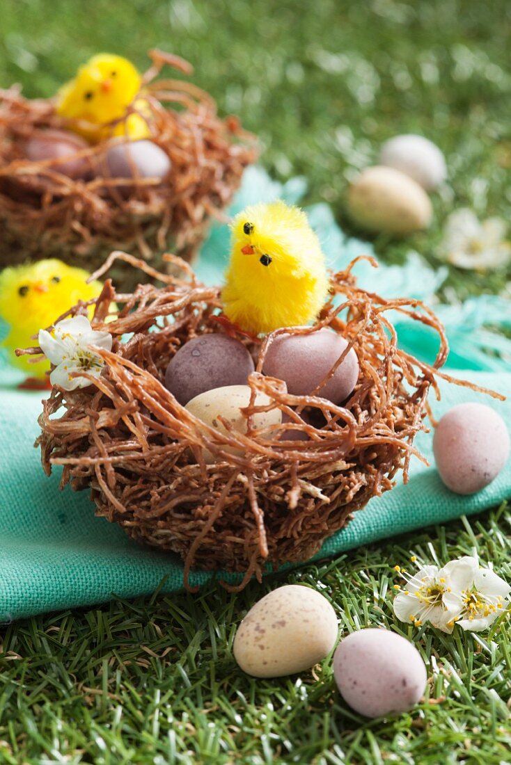 Osternest mit Schokoladeneiern und Osterküken auf Wiese