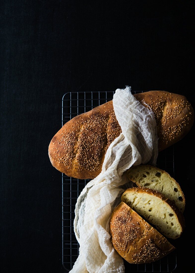 Italian semolina bread on a cooling rack against a black background