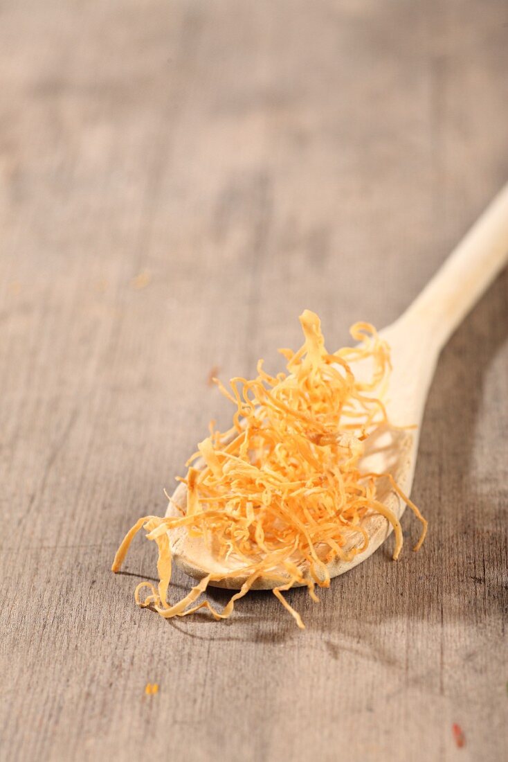 Fried shoestring potato on a wooden spoon