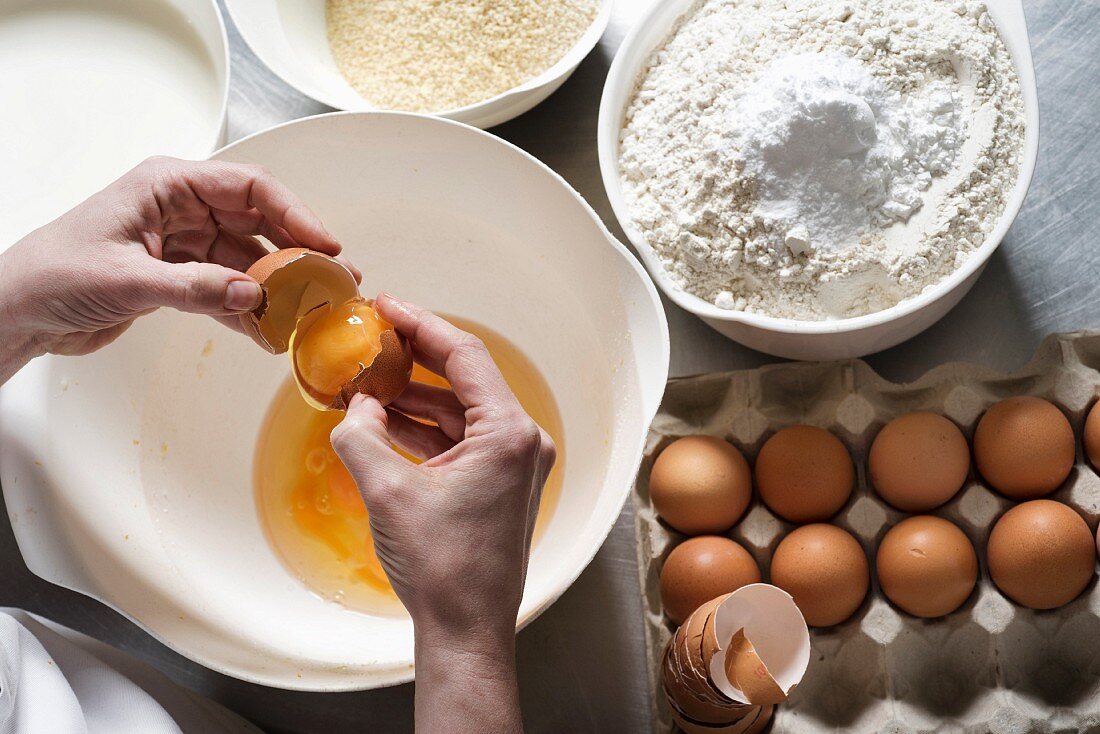 Ei über Schüssel aufschlagen, daneben Mandelmehl und Mehl mit Backpulver