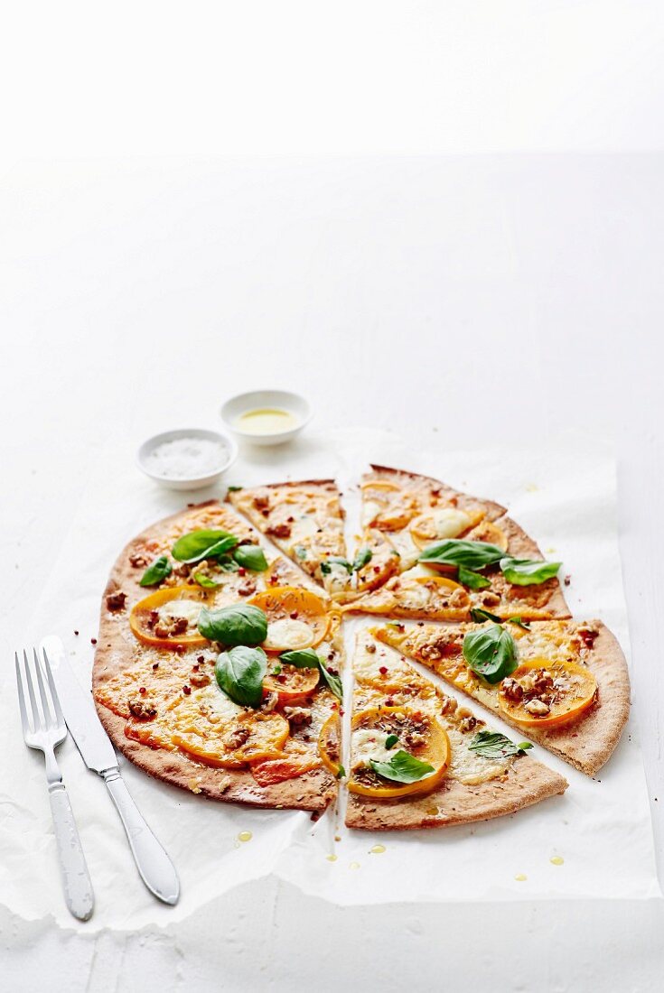 Gluten-free homemade pizza with persimmons, goat's cheese and basil