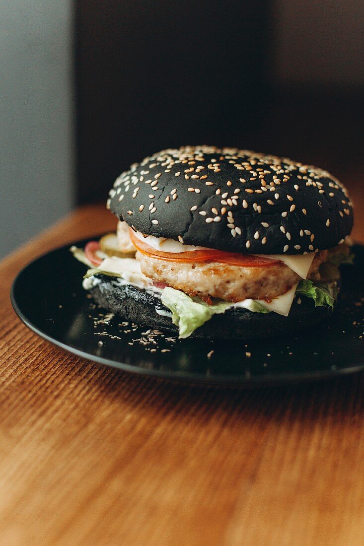 Schwarzer Burger mit Käse, Tomaten und Salat