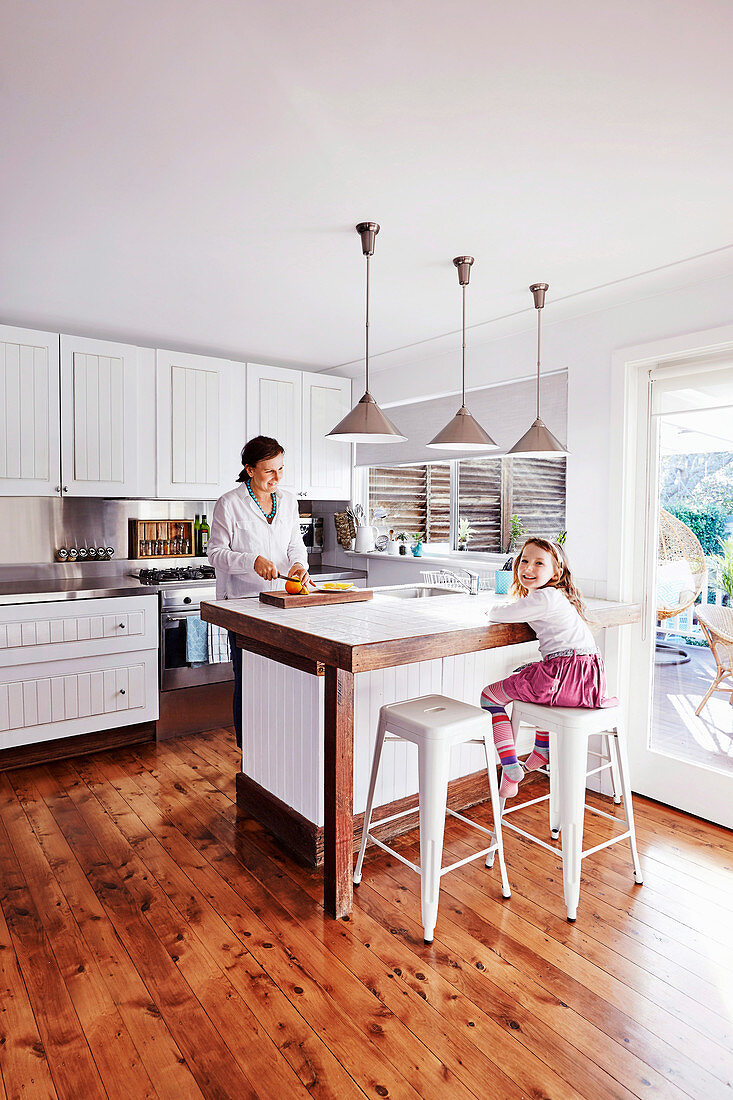 Mother and daughter in white, open kitchen with wooden floor