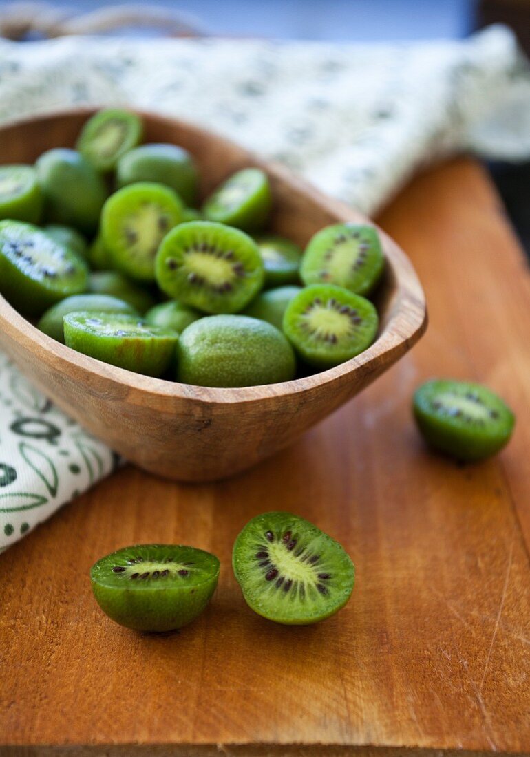 Kiwi berries (mini kiwi) in a wooden bowl on a rustic wooden surface