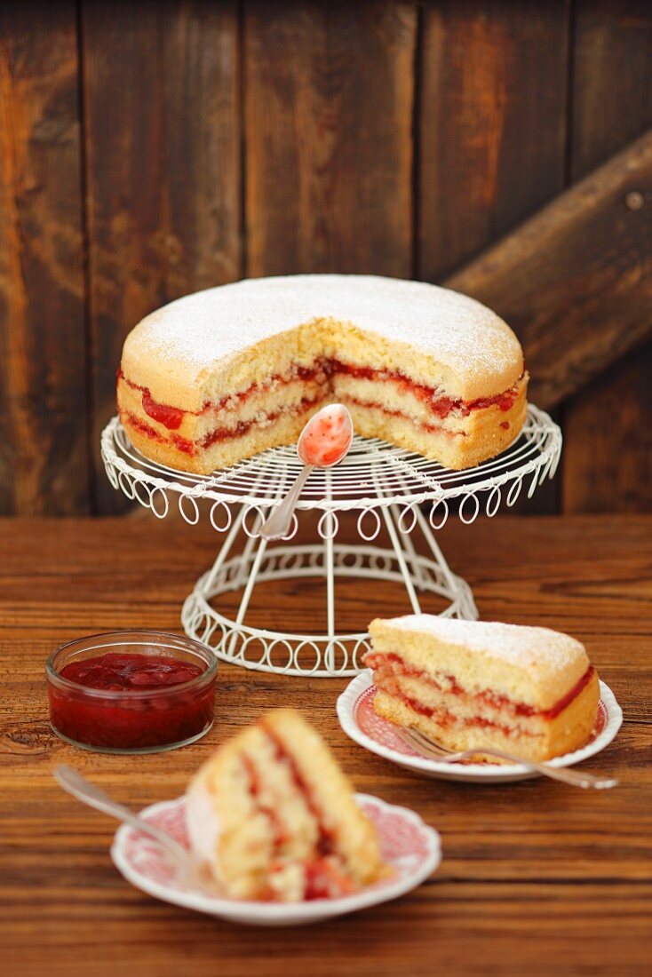 Victoria sponge cake with strawberry jam on a cake rack