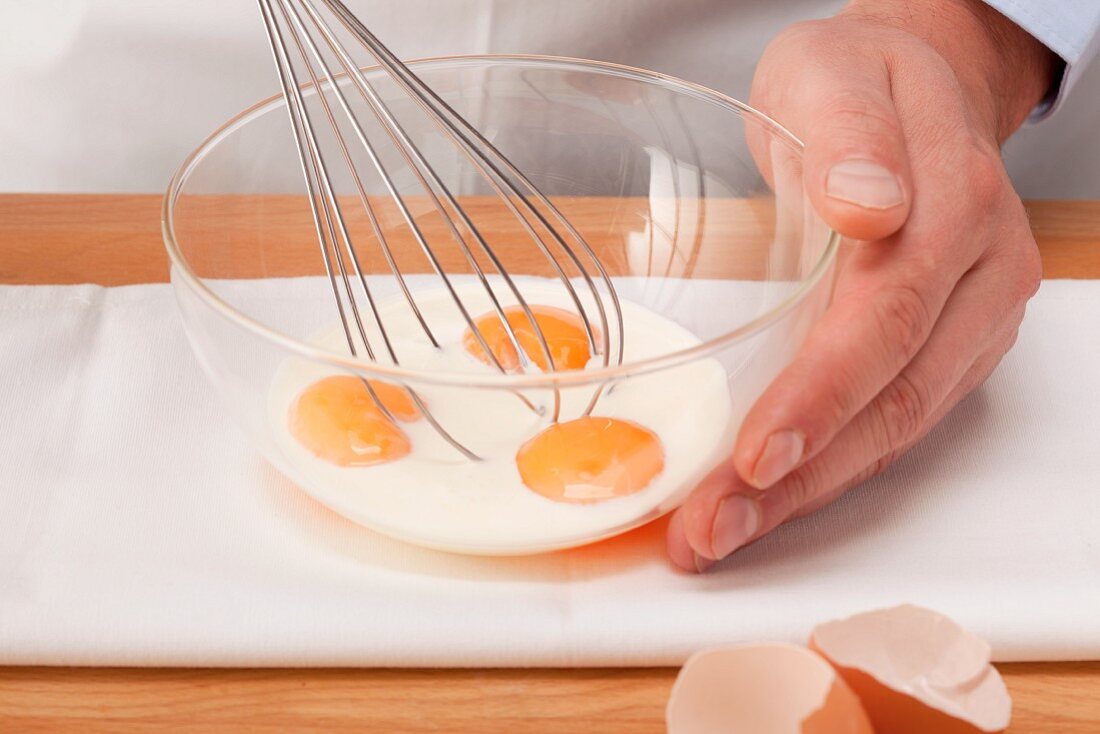 Egg yolks being mixed with milk to thicken sauce