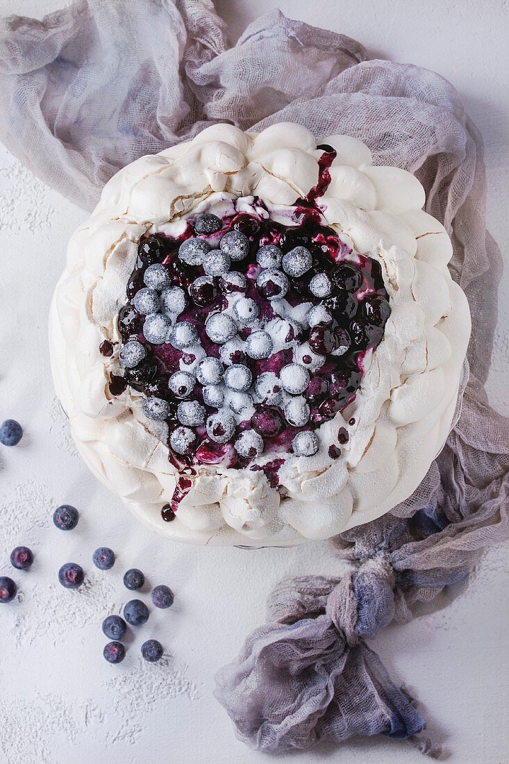 Homemade meringue cake Pavlova with whipped cream, sugar powder, fresh blueberries and blueberry sauce