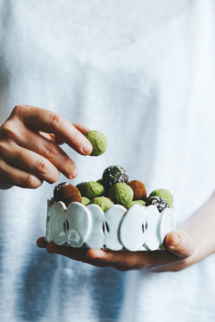 A woman holding a bowl of mixed matcha and chocolate homemade sweets