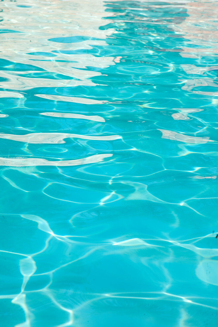 Reflections of sunlight on blue water in swimming pool