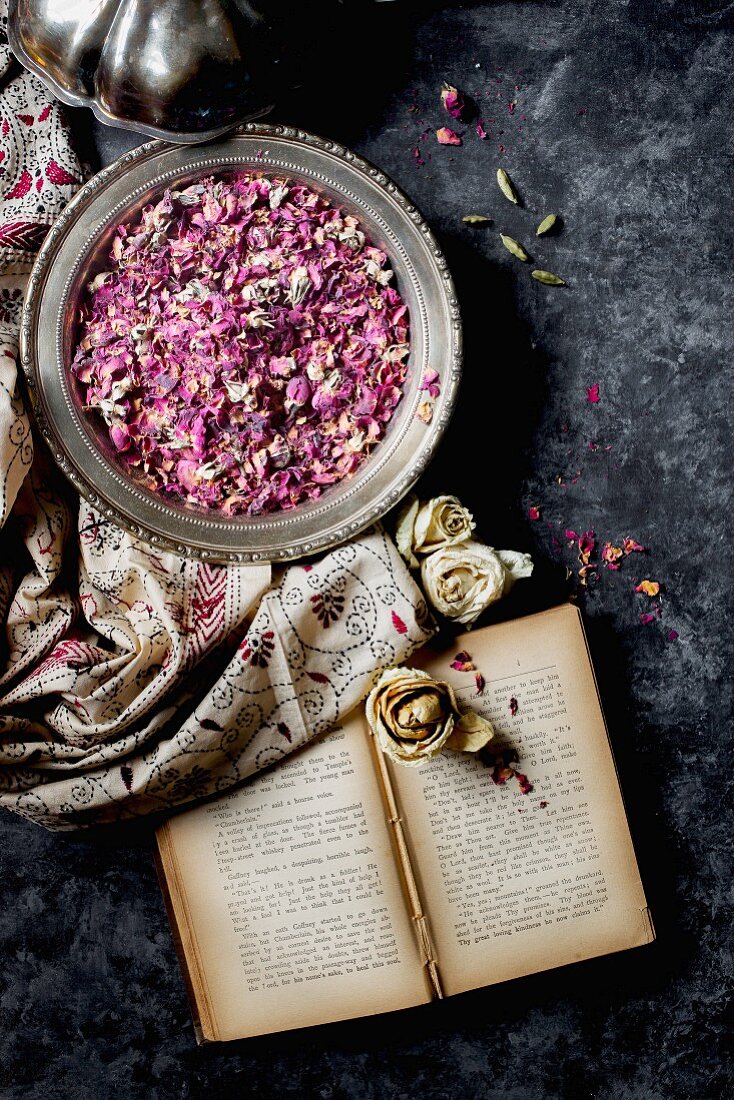 Nostalgisches Stillleben mit Buch und getrockneten Rosenblüten in Silberschale