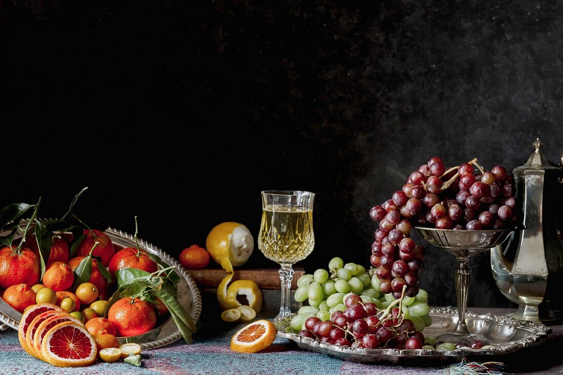 Obststillleben im Stil eines Gemäldes mit Zitrusfrüchten, Trauben und Wein