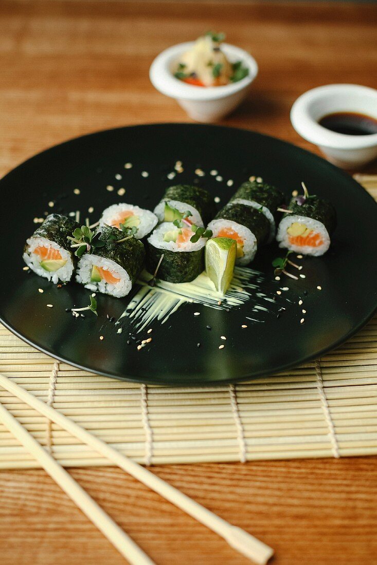Maki Sushi mit Lachs und Avocado auf schwarzem Teller