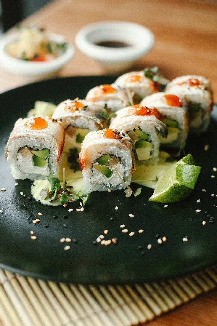 Sushi with fish, avocado and fresh cheese on a black plate