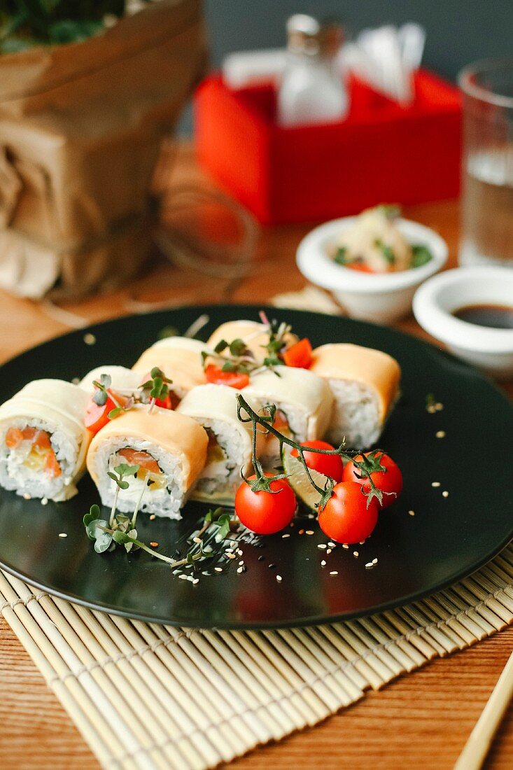 Sushi rolls with salmon, fresh cheese and cocktail tomatoes