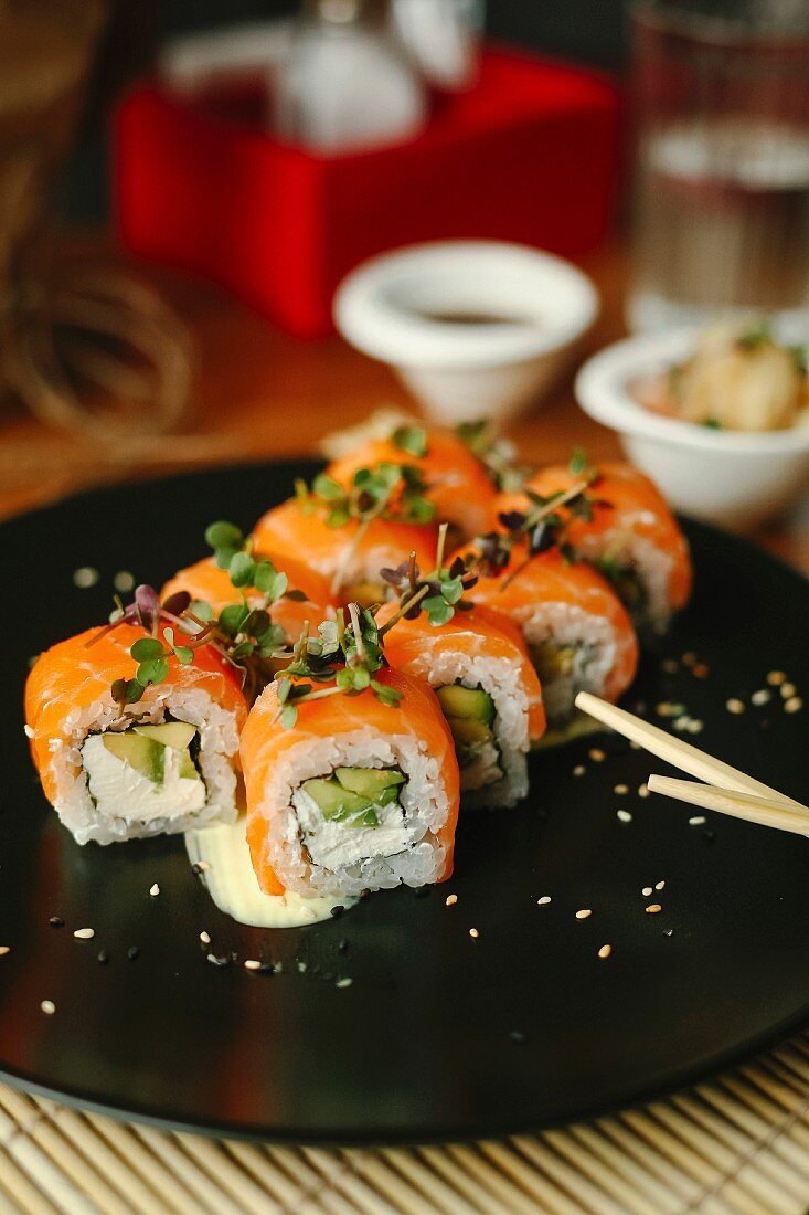 Sushi rolls with salmon, avocado, fresh cheese and herbs