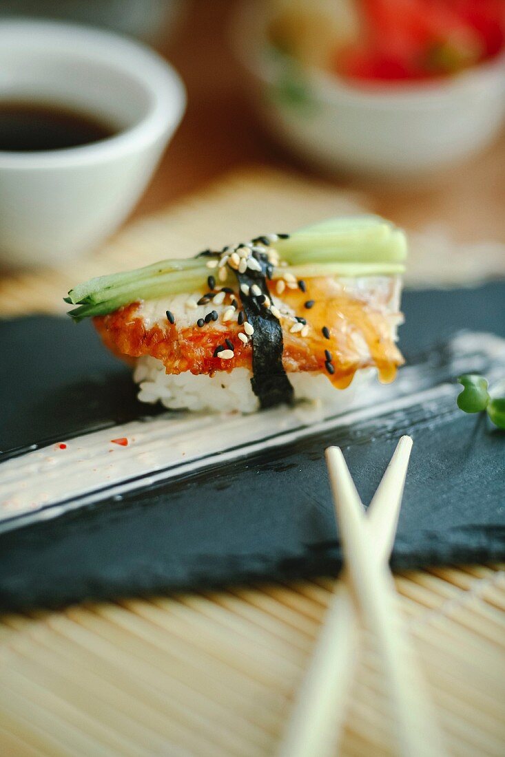 Nigiri sushi with white fish and cucumber on a black plate