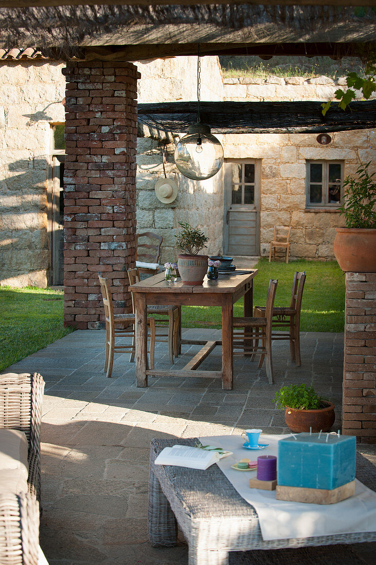 Wooden table on roofed terrace in Mediterranean garden