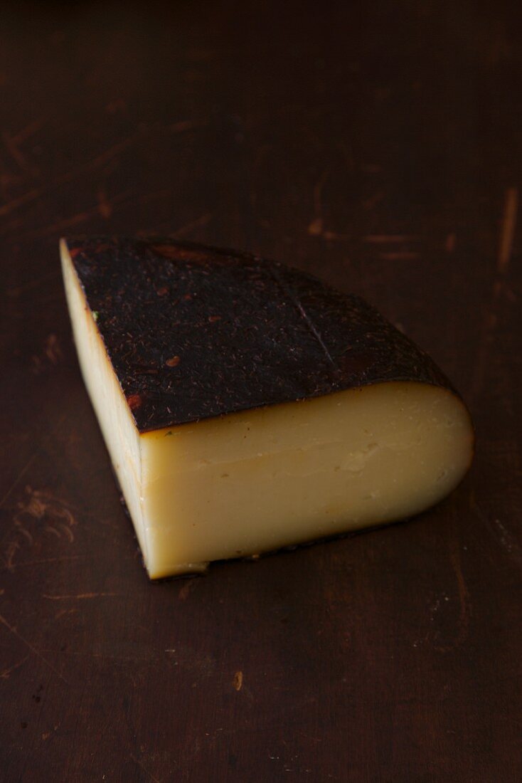 Ein Stück Käse auf braunem Holzuntergrund