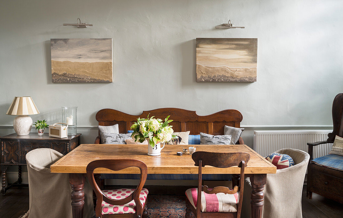 Various chairs and bench around table below maritime pictures on wall