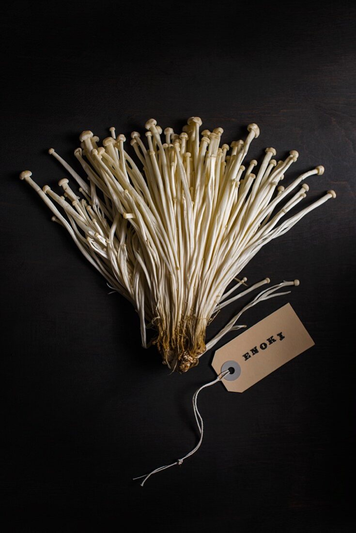 Fresh Enoki mushrooms against a black background (top view)