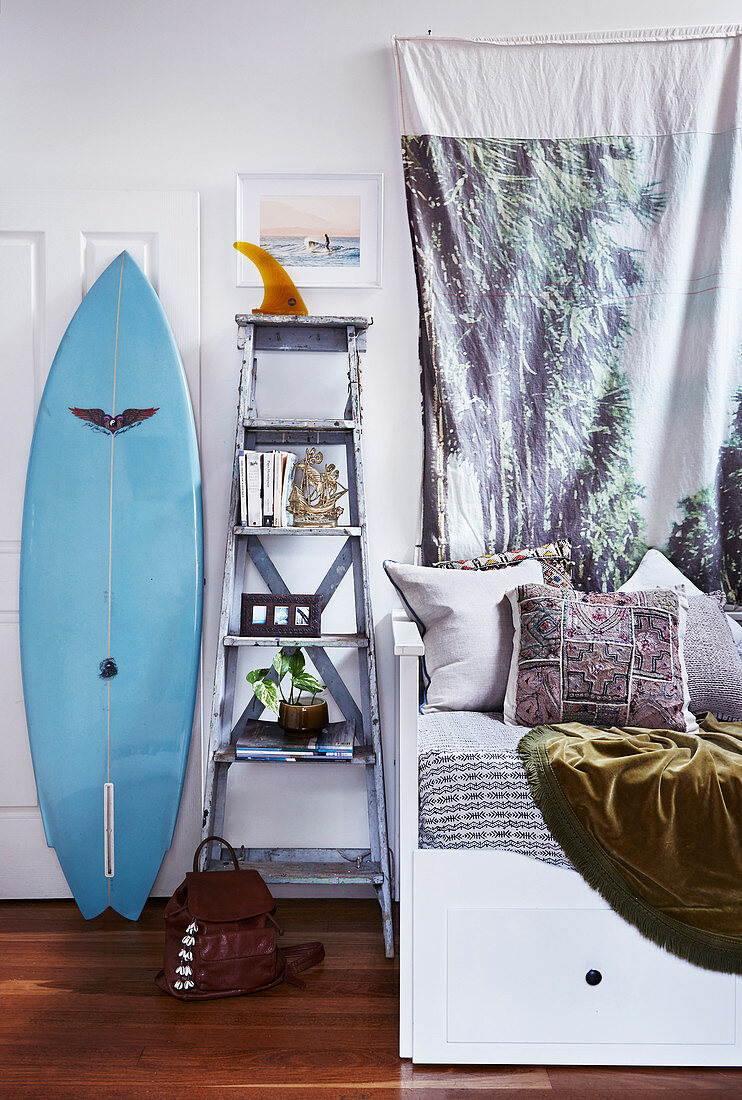 Bed with pillows, next to ladder shelf and surf bed
