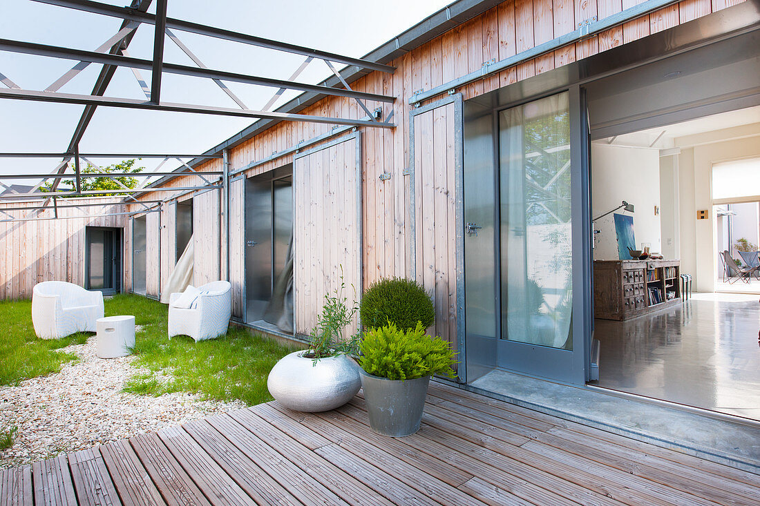 Modern wooden house enclosing seating and terrace in courtyard