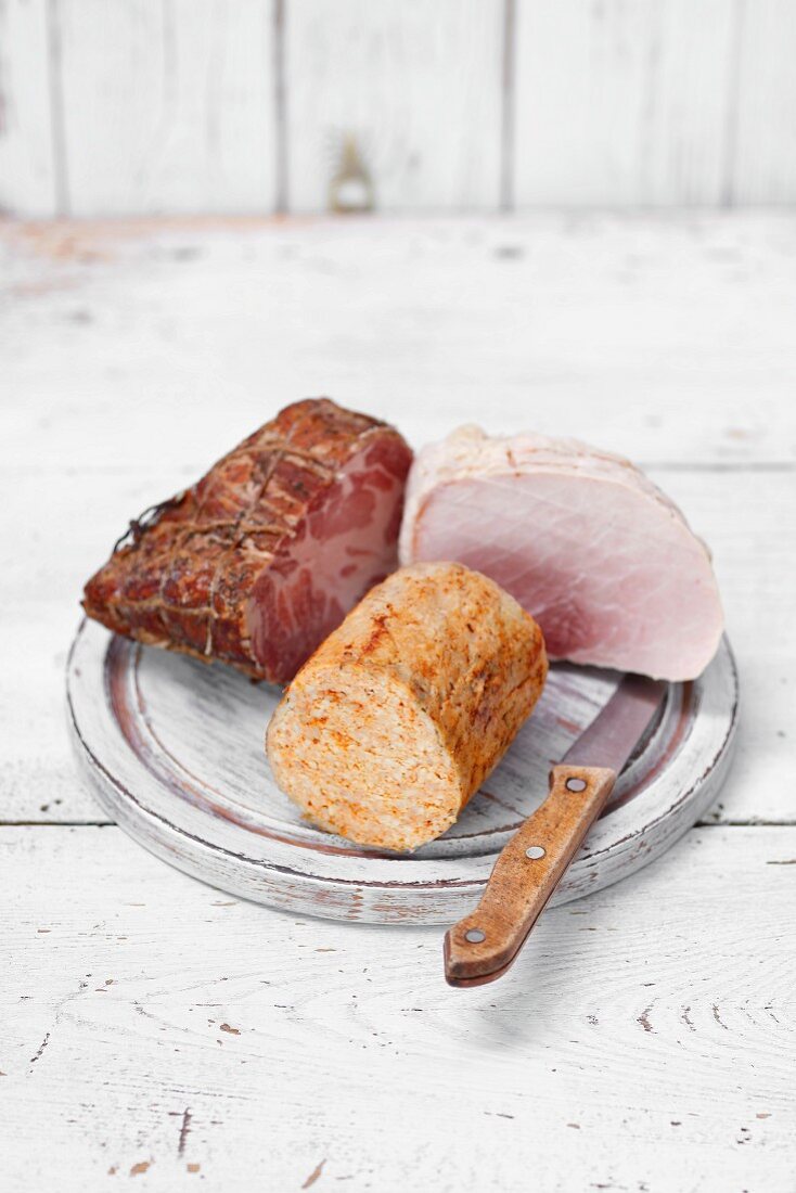 Pieces of pork ham and poultry roulade on a wooden board