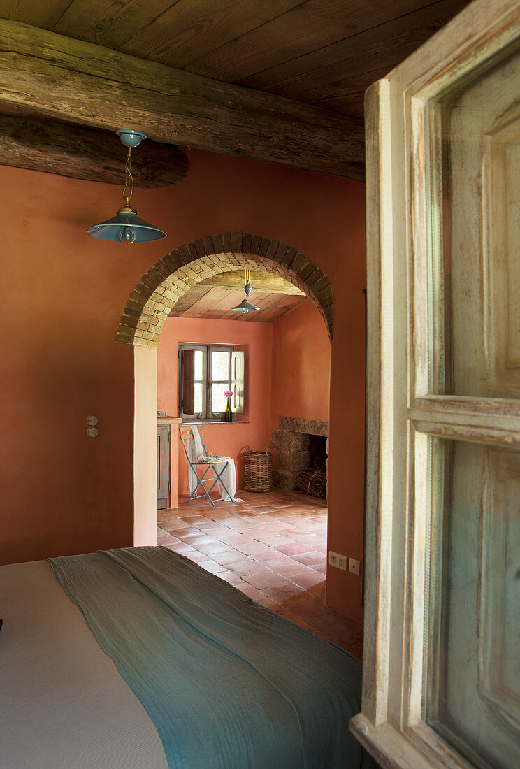 View from bedroom through arched doorway to fireplace beyond