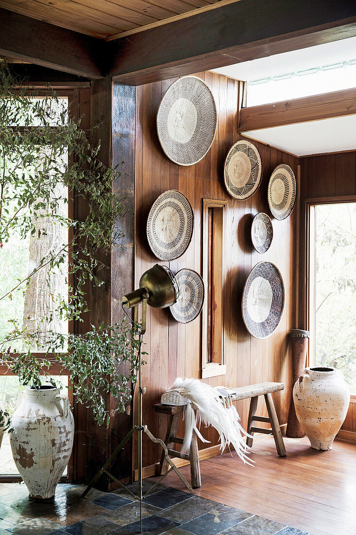 Moroccan plates on a wood-clad wall, including a rustic bench