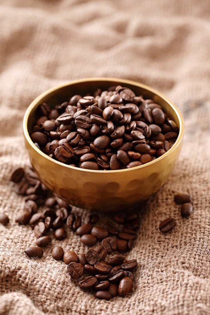 Coffee beans in a metal bowl on a jute cloth