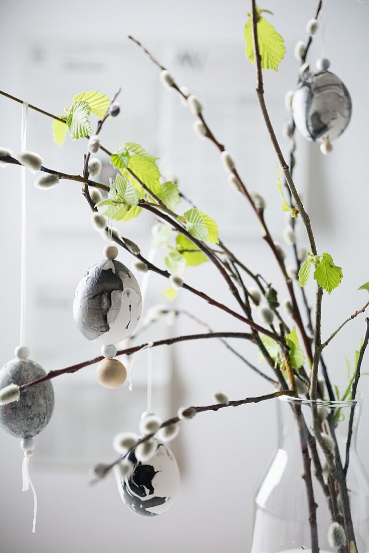 Marbled Easter eggs hung from willow and beech branches in vase